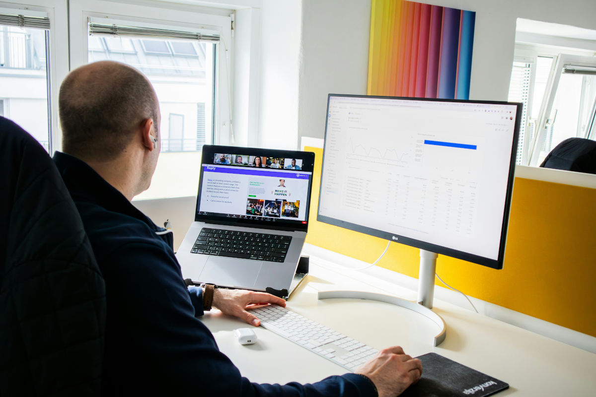 Web designer at a desk reviewing a page layout on a large monitor next to a laptop, representing recruitment website structured data and template planning